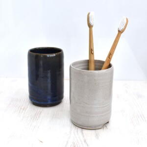 Two bamboo toothbrushes in a grey Clod & Pebble ceramic toothbrush holder