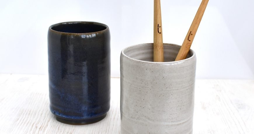 Two bamboo toothbrushes in a grey Clod & Pebble ceramic toothbrush holder