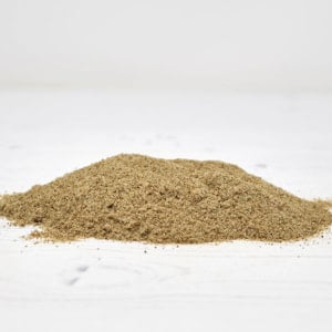 A conical mound of coarse, beige celery salt resting on a white wood-grain surface.